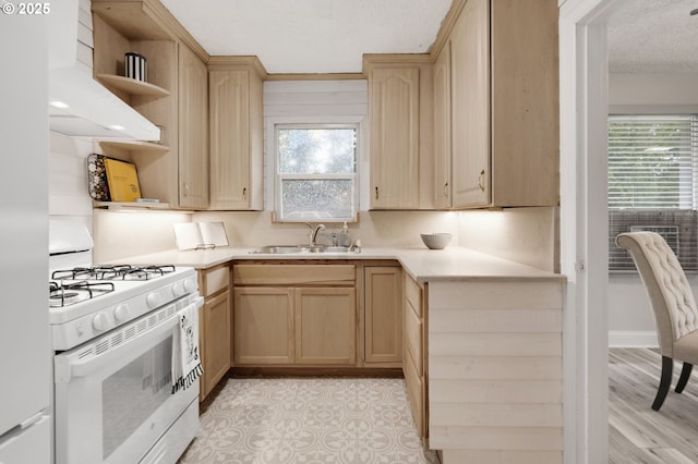 kitchen featuring gas range gas stove, a sink, light brown cabinets, open shelves, and a textured ceiling