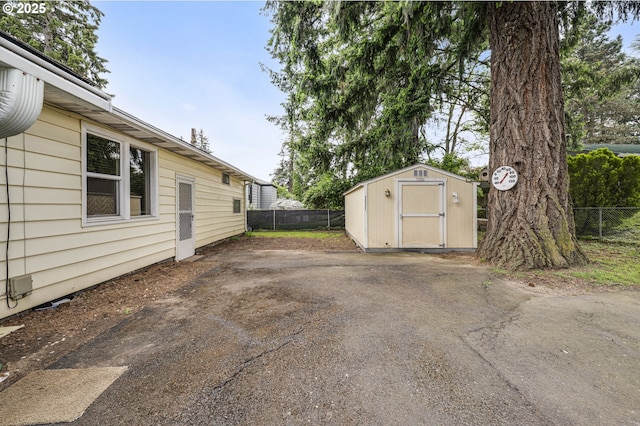 view of side of property featuring a storage shed, fence, and an outbuilding
