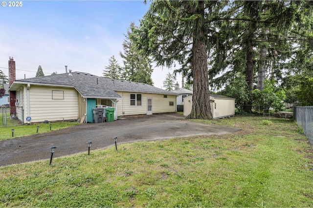 rear view of house featuring a storage shed, an outbuilding, and driveway