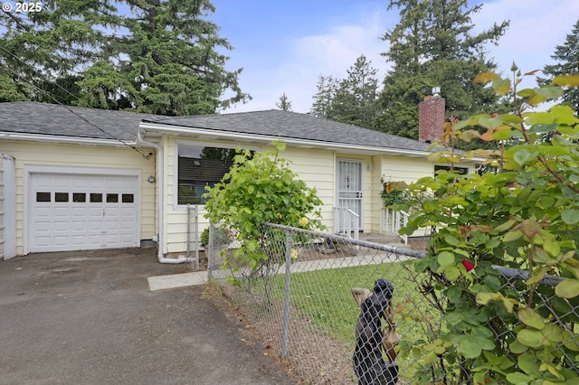 ranch-style house with driveway, fence, a chimney, an attached garage, and a shingled roof