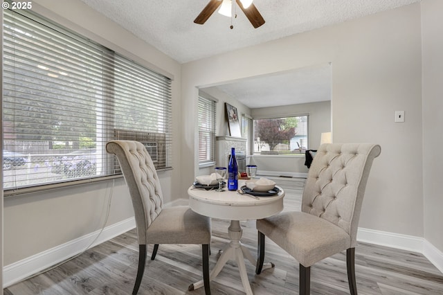 dining area with wood finished floors, a ceiling fan, a textured ceiling, and baseboards