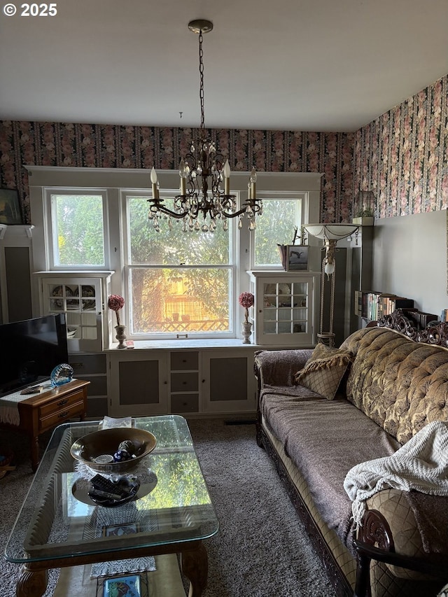 carpeted living room featuring an inviting chandelier and wallpapered walls