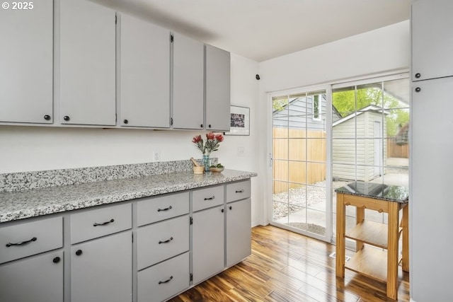 kitchen featuring light wood-style flooring, gray cabinets, and light stone counters