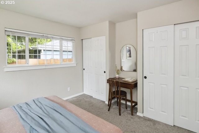 bedroom with two closets, carpet flooring, and baseboards