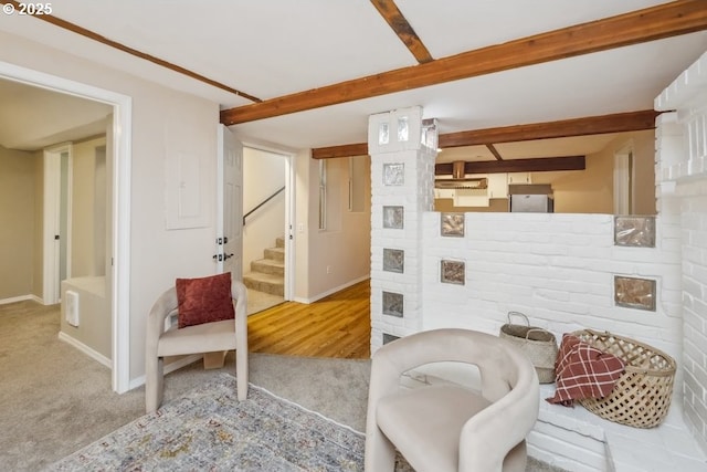 living room featuring beamed ceiling, carpet floors, stairs, and baseboards