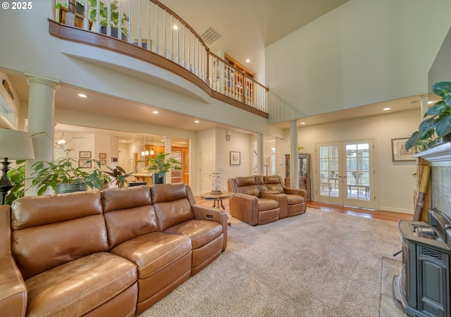 living area featuring a high ceiling, wood finished floors, visible vents, french doors, and ornate columns