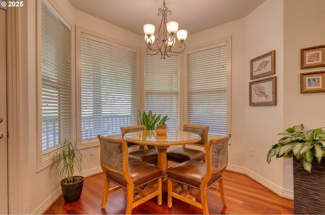 dining area featuring light wood-style flooring, baseboards, and a notable chandelier