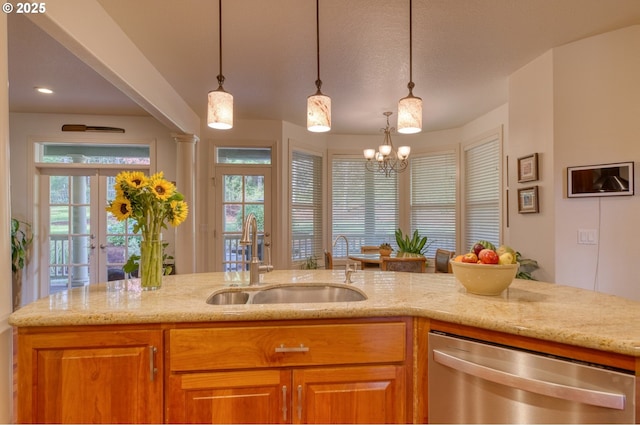 kitchen with light stone counters, a sink, hanging light fixtures, brown cabinets, and dishwasher