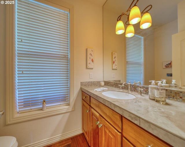 bathroom featuring toilet, baseboards, wood finished floors, and vanity