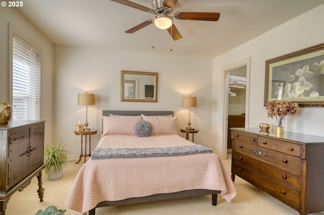 bedroom with a walk in closet, a closet, a ceiling fan, light carpet, and baseboards