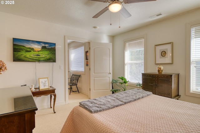 bedroom featuring carpet, multiple windows, visible vents, and a textured ceiling