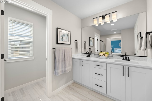 bathroom featuring double vanity, baseboards, a sink, and ensuite bathroom