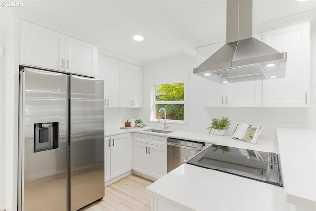 kitchen featuring stainless steel appliances, a sink, white cabinetry, and wall chimney range hood