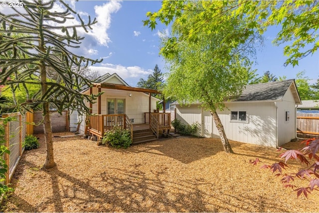 rear view of house with a wooden deck, french doors, an outbuilding, and a fenced backyard