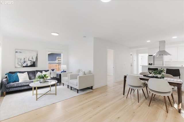 living area with baseboards, recessed lighting, and light wood-type flooring