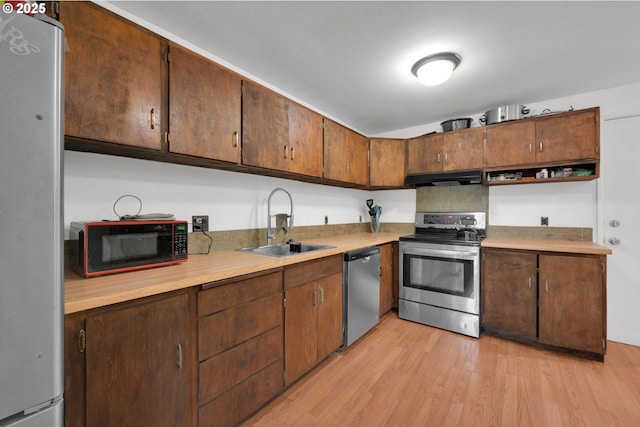 1438 Quaker St, Eugene, OR 97402 - kitchen with appliances with stainless steel finishes, under cabinet range hood, a sink, light wood-style floors, and light countertops