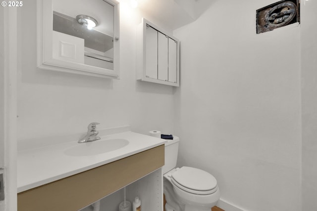 half bath featuring vanity, toilet, and baseboards