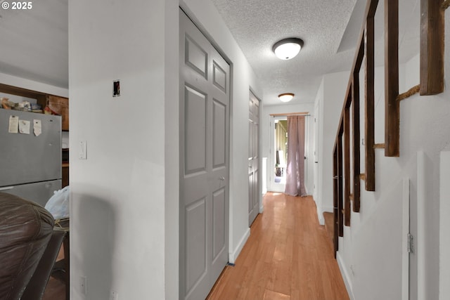 1438 Quaker St, Eugene, OR 97402 - hall featuring light wood-type flooring, a textured ceiling, stairway, and baseboards