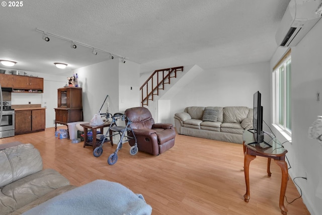 1438 Quaker St, Eugene, OR 97402 - living area featuring a wall unit AC, light wood finished floors, stairs, a textured ceiling, and track lighting