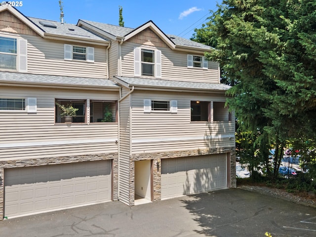 12130 NE Fremont St Unit 4, Portland, OR 97220 - view of property featuring driveway, a garage, stone siding, and roof with shingles