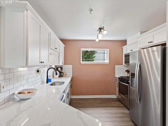 12130 NE Fremont St Unit 4, Portland, OR 97220 - kitchen featuring stainless steel appliances, tasteful backsplash, white cabinetry, wood finished floors, and light stone counters