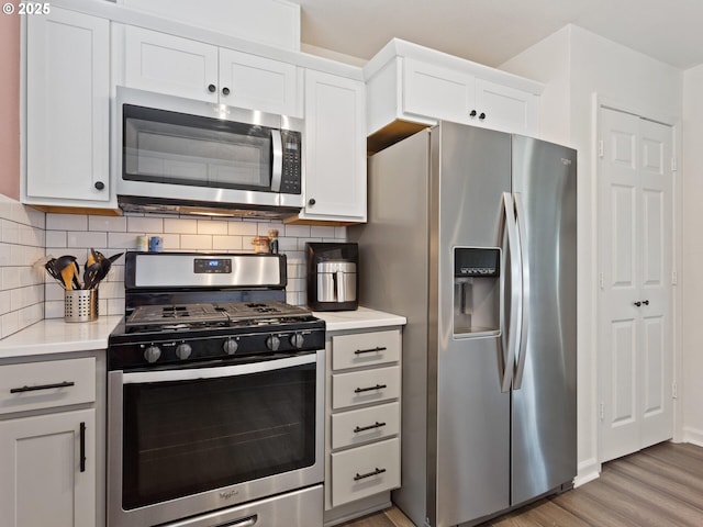 12130 NE Fremont St Unit 4, Portland, OR 97220 - kitchen featuring stainless steel appliances, light wood-type flooring, light countertops, backsplash, and white cabinetry