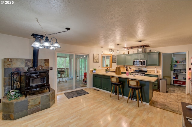 82548 Vinemaple Rd, Seaside, OR 97138 - kitchen featuring appliances with stainless steel finishes, a peninsula, light countertops, green cabinetry, and a textured ceiling