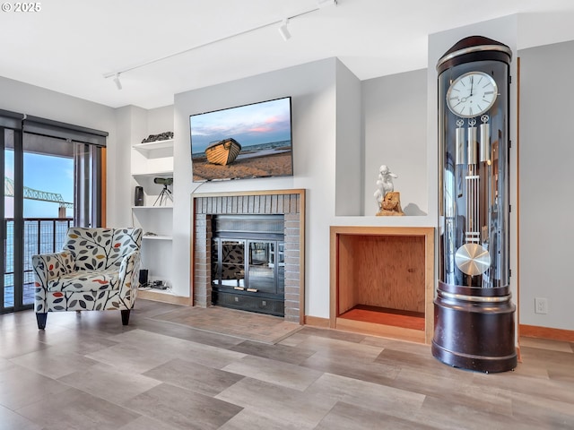 1 3rd St Unit 204, Astoria, OR 97103 - living room with rail lighting, a brick fireplace, built in features, and baseboards
