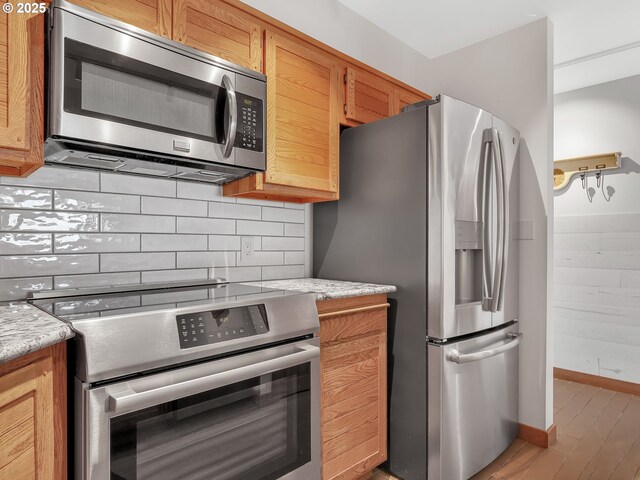 1 3rd St Unit 204, Astoria, OR 97103 - kitchen with stainless steel appliances, backsplash, light wood-type flooring, and baseboards