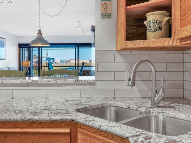 1 3rd St Unit 204, Astoria, OR 97103 - kitchen view of a sink, decorative backsplash, light stone countertops, and hanging light fixtures