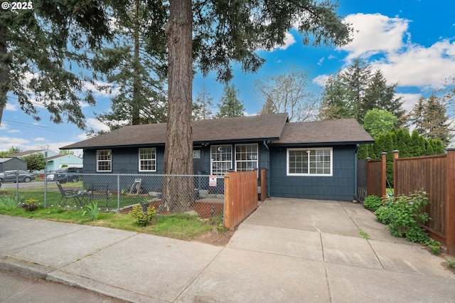 ranch-style home with a shingled roof and a fenced front yard