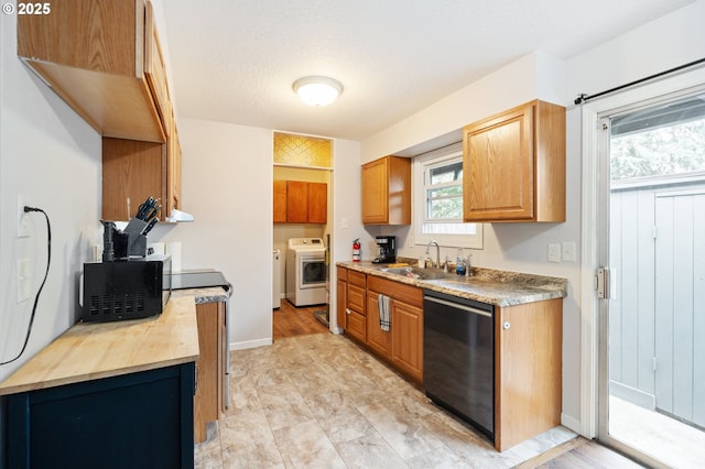 kitchen featuring black microwave, dishwasher, a sink, light countertops, and washer and dryer