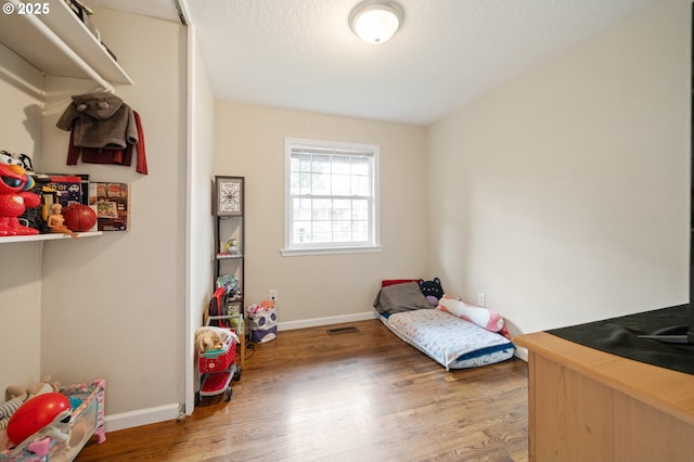bedroom with baseboards, visible vents, and wood finished floors