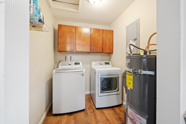 clothes washing area with cabinet space, light wood-style flooring, water heater, washer and clothes dryer, and electric panel