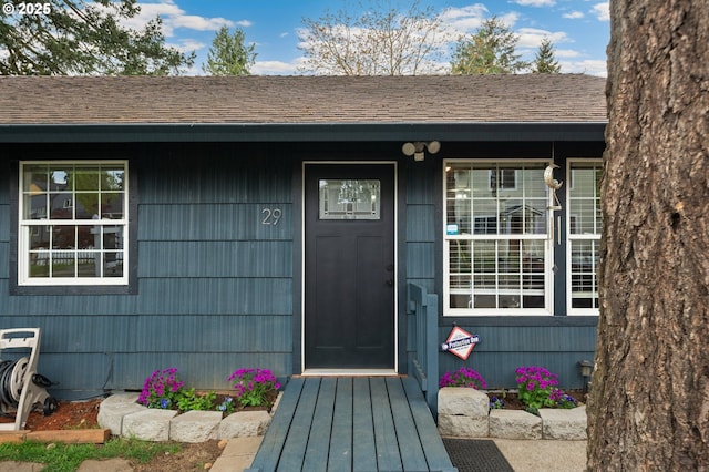 doorway to property with a shingled roof