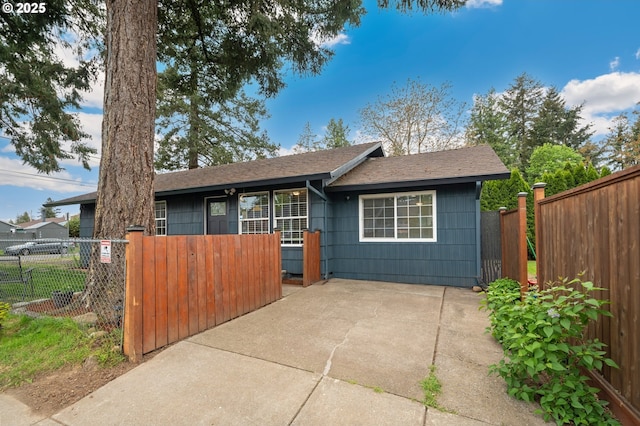 ranch-style home featuring roof with shingles and a fenced front yard