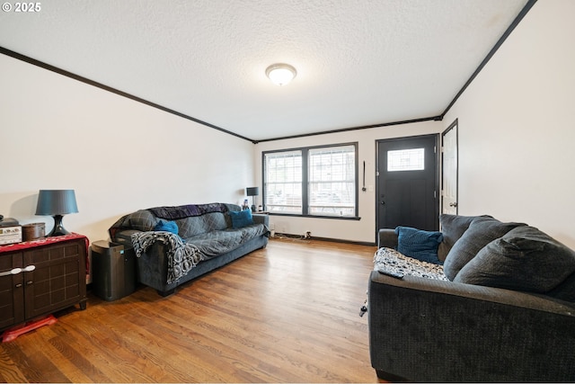 living area with a textured ceiling, ornamental molding, and wood finished floors