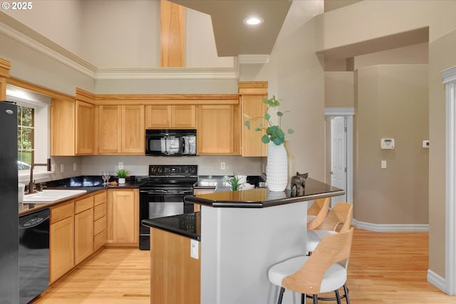 15564 S Neibur Rd, Oregon City, OR 97045 - kitchen featuring a sink, light wood finished floors, light brown cabinets, a kitchen bar, and black appliances