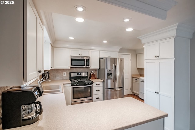 kitchen with sink, stainless steel appliances, white cabinetry, and kitchen peninsula