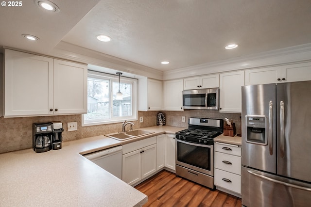 kitchen with appliances with stainless steel finishes, decorative light fixtures, white cabinetry, decorative backsplash, and sink