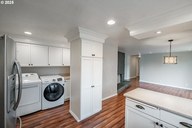 laundry room featuring a brick fireplace, cabinets, washing machine and dryer, and dark wood-type flooring