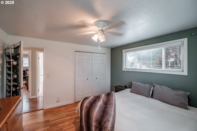 bedroom with ceiling fan, multiple windows, a closet, and light hardwood / wood-style flooring