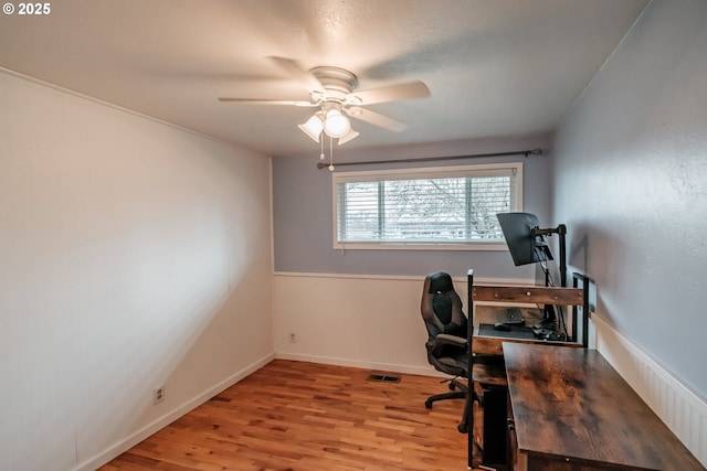 office with light wood-type flooring and ceiling fan