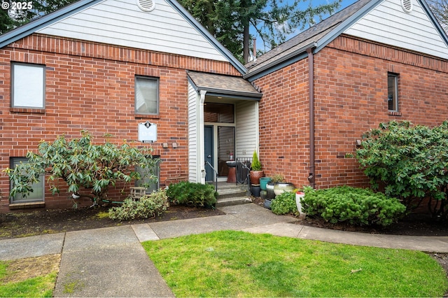 view of front of home with a shingled roof and brick siding