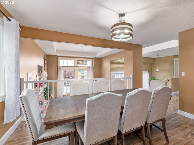 dining area featuring baseboards, a notable chandelier, wood finished floors, and a tray ceiling