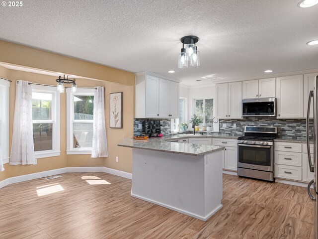 kitchen featuring baseboards, light wood-type flooring, white cabinetry, tasteful backsplash, and stainless steel appliances