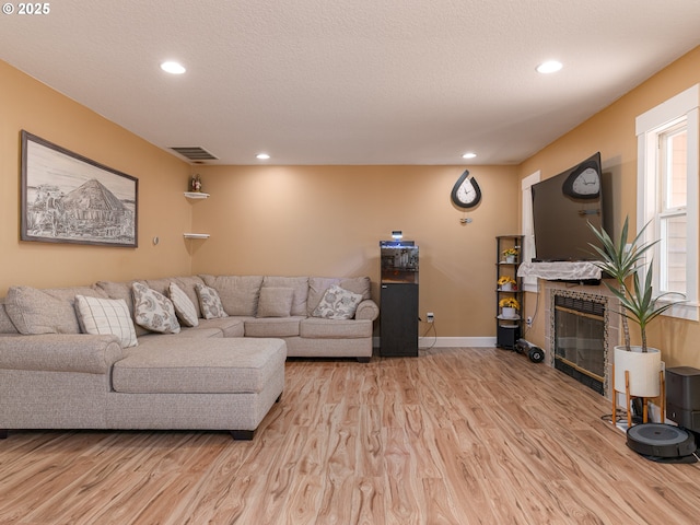 living room with recessed lighting, visible vents, light wood finished floors, and a tile fireplace