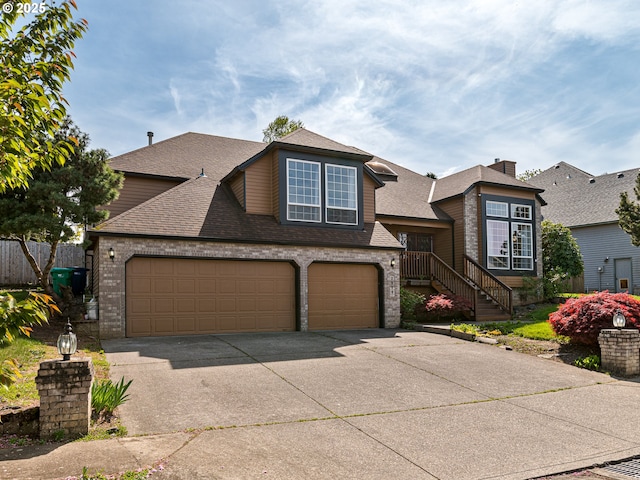 traditional home featuring a garage, fence, roof with shingles, brick siding, and concrete driveway