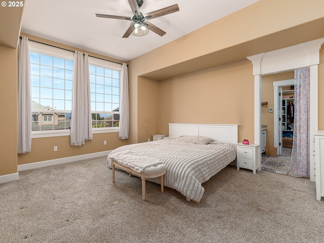 bedroom featuring baseboards, carpet flooring, a ceiling fan, and a walk in closet