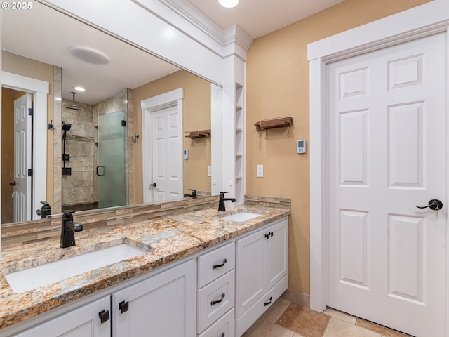 full bathroom featuring a sink, a textured wall, a stall shower, and double vanity